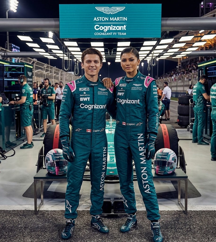 Man and woman in teal Aston Martin Cognizant-style racing suits in the pits