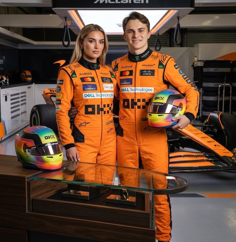 Man and woman in orange McLaren racing suits with an F1 helmet
